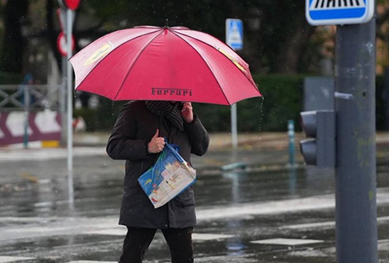 Un hombre se protege de la lluvia bajo su paraguas .